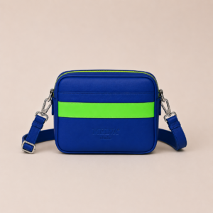 Vegane Crossbody Bag in Royal Blue mit neon-mintfarbenem Statement-Streifen, neon-mintfarbenem Reißverschluss und hochglänzenden silberfarbenen Metallelementen von MELVA° Studio.