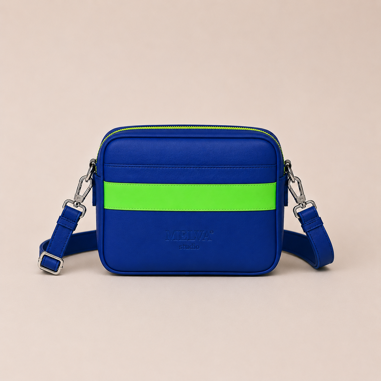 Vegane Crossbody Bag in Royal Blue mit neon-mintfarbenem Statement-Streifen, neon-mintfarbenem Reißverschluss und hochglänzenden silberfarbenen Metallelementen von MELVA° Studio.
